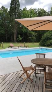 a wooden deck with a table and umbrella next to a pool at Lodge de Loire - B & B proche Chambord in Saint Laurent Nouan