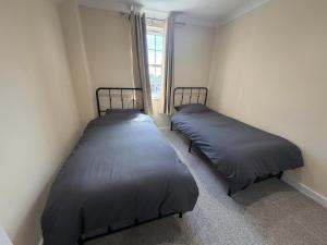 two beds in a small room with a window at Ely Stays City Center 2 Bedroom Flat in Ely