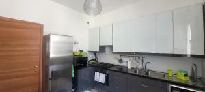 a kitchen with white cabinets and a stainless steel refrigerator at Margot's House Rho in Rho