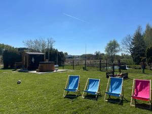 three chairs sitting in the grass in a field at Apartamenty TUTERRA I in Zabagnie