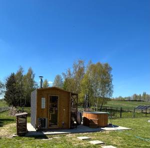 a small wooden shed with a tub in a field at Apartamenty TUTERRA I in Zabagnie
