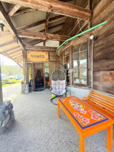 a wooden building with a bench and a chair at ペンションminiモンゴル in Makito