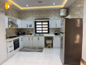 a kitchen with white cabinets and a stainless steel refrigerator at دور فخم كامل 6 غرف بحوش خاص ومدخل سيارة in Taif