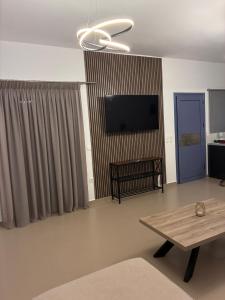 a living room with a flat screen tv and a table at Nenes Comfort Apartment in Koroni