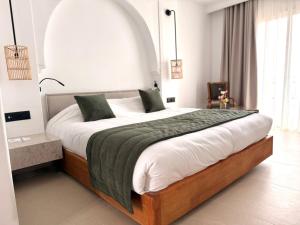 a bedroom with a large bed with white sheets and green pillows at Al Jazira Beach & Spa- All Inclusive - Families and Couples Only in Houmt Souk