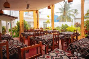 a restaurant with tables and chairs and a palm tree at Karibu House Paje in Paje