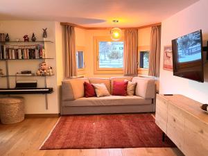a living room with a couch and a television at Chesa Silvretta - Celerina in Celerina