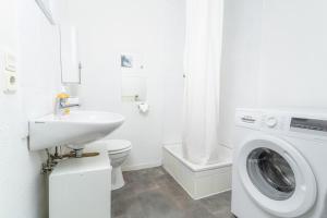 a white bathroom with a sink and a washing machine at fewo1846 - Smutjes Koje - für eine entspannte Auszeit mit Balkon im Stadtzentrum in Flensburg