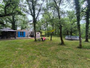 a person sitting on a bench in a yard with trees at Le Refuge des Bois de Morphée in Escamps +2 photos