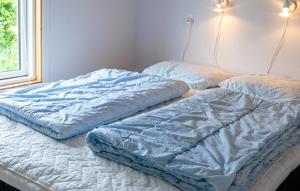 two unmade beds in a room with a window at Nice Apartment In Farsø With Heated Swimming Pool in Farsø