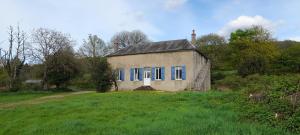 an old house with blue windows in a field at Le Gite des Sources in Lormes