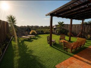 a backyard with benches and a hammock on the grass at Villa Twins in Lajares