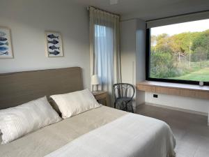 a bedroom with a bed and a large window at Casa Cortaderas, Barrio Quequén Chico in Necochea