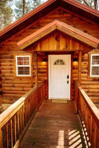 a cabin with a white door on a wooden porch at Cardinal's Crest in Logan