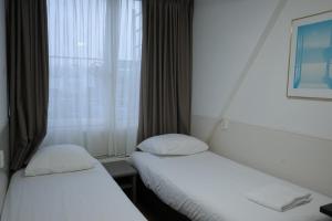 two beds in a hotel room with a window at Hotel Sphinx in Amsterdam +25 photos