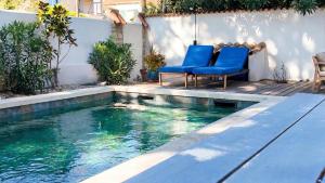 a swimming pool with blue chairs next to a house at Lis Oureto in Saint-Cyr-sur-Mer