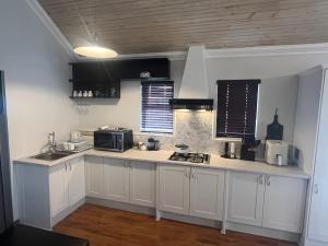 a kitchen with white cabinets and a microwave at Serenity Suite in Somerset West