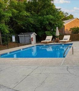 a swimming pool with two chairs and a table at Tiny Palace - 1-Bedroom Apartment - Multi-Week Stay - Pool - Washer-Dryer - Dog-friendly with fee for 1 Family Pet in Wilmington