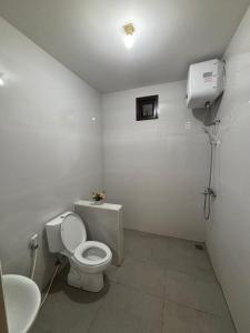 a white bathroom with a toilet and a sink at Base Seven Hostel in Bandung