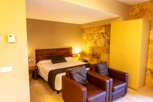 a bedroom with a bed and two chairs at L'Arcada de Fares in Sant Ferriol +50 photos
