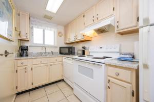 a kitchen with white appliances and wooden cabinets at Driftwood Towers 6D condo in Gulf Shores +23 photos