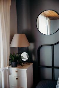 a bedroom with a lamp on a dresser and a mirror at Avotu rezidence Apē in Ape