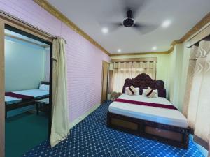 a bedroom with a large bed in a pink room at Hotel Aanandalok in Pānigata