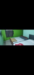 a room with two beds and a green wall at HOTEL SEA ROCk in Belagula