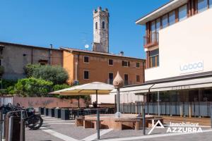 a building with a clock tower in the background at Aly d'Angelo alla Torre - Immobiliare Azzurra in Bardolino