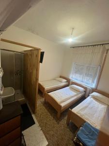 a room with two beds and a bathroom with a shower at Sobe Kovacevic in Cvijetići