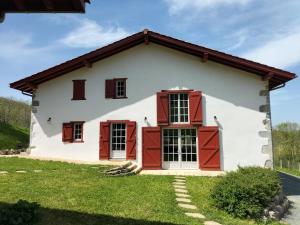 a white house with red doors and windows at Maison basque de charme avec piscine in Souraïde