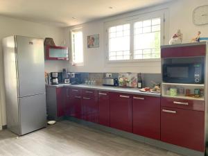 a kitchen with red cabinets and a refrigerator at Chez Chris in Jard-sur-Mer