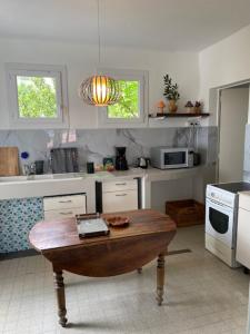 a kitchen with a table in the middle of it at Le Chêne in Villeneuve