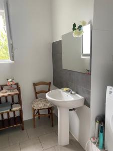 a white bathroom with a sink and a chair at Le Chêne in Villeneuve