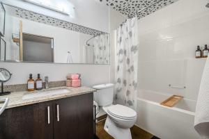 a bathroom with a toilet and a sink and a tub at Jungle Book Luxe Suite Downtown BMO in Calgary
