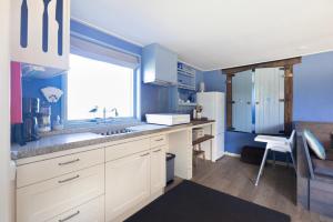 a kitchen with white cabinets and a blue wall at De Zilverreiger op camping Oudesluis in Oudesluis