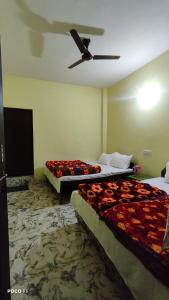 a hotel room with two beds and a ceiling fan at The Kedar Heights in Gupta Kāshi