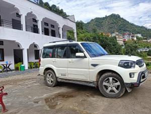 a white jeep parked in front of a building at Panchkedar resort in Sonprayag +3 photos