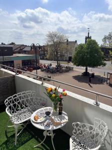 a table and chairs on a balcony with a city street at Two Floor Flat in Town Center in Kenilworth