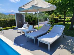 a group of chairs and an umbrella next to a pool at Sea & Summit Pool Villa in Platamonas