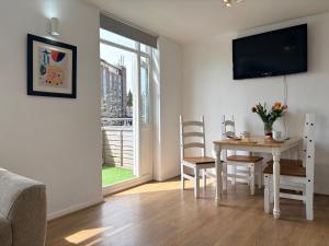 a living room with a table and chairs and a television at Two Floor Flat in Town Center in Kenilworth