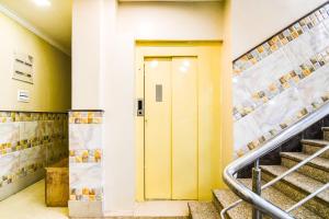 a yellow door in a building with stairs at Hotel O Barsana in Pātipukur