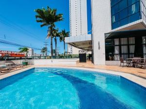 a large blue swimming pool next to a building at Plaza Suíte Natal Vista Mar in Natal
