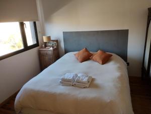 a bedroom with a large white bed with towels on it at Cabaña San Charbel in Potrerillos
