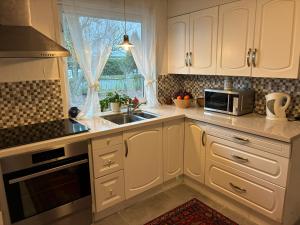 a kitchen with white cabinets and a sink and a window at Risskov sommerhus in Risskov