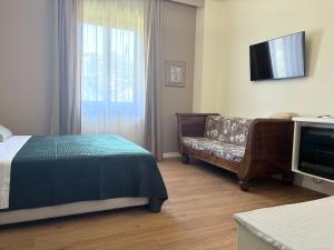 a bedroom with a bed and a couch and a television at Alle porte di Spello in Spello