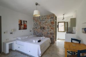 a bedroom with a bed and a stone wall at Dimitra Studios in Aegiali