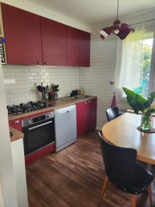 a kitchen with red cabinets and a wooden table at Charmante maison in Dinard