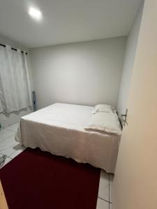 a small bedroom with a white bed and a red rug at Apartamento in Campo Largo