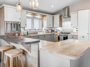 a kitchen with white cabinets and a wooden counter top at Turnberry Lodge in Girvan